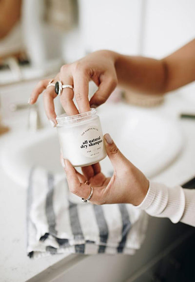 a woman pulling dry shampoo out of a jar