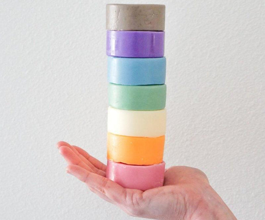 a hand holding a stacked tower of conditioner bars