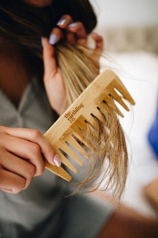 a close-up of someone using an earthling co bamboo comb